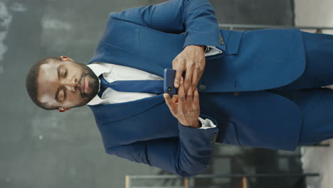 american smiling businessman texting and chatting on smartphone in the office