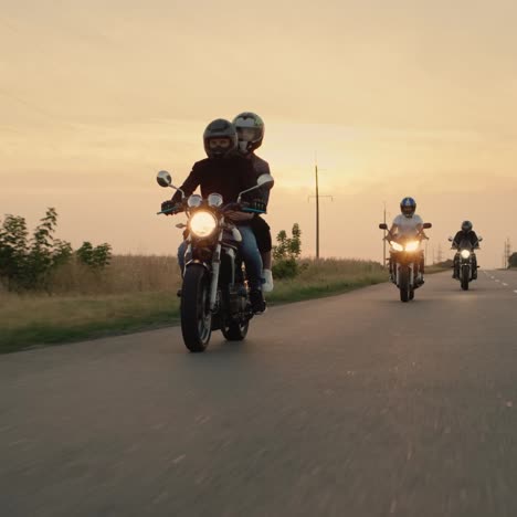 three bikers drive on the highway at sunset