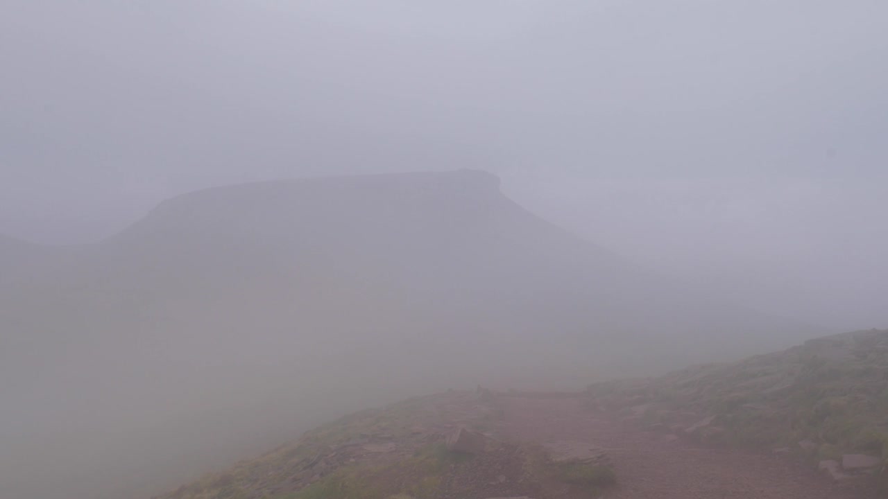 Clouds and fog slowly rolling over Pen y Fan in Brecon Beacon hills, Wales, UK 4K
