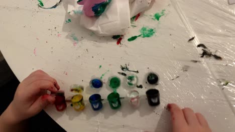 the child is playing with paint containers. colorful paint containers for creative play at home