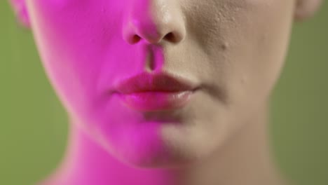 close up of woman's mouth eating strawberry fruit, studio shot with colorful lighting