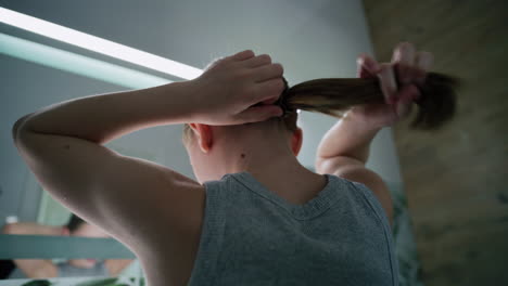 child tying her hair in the bathroom