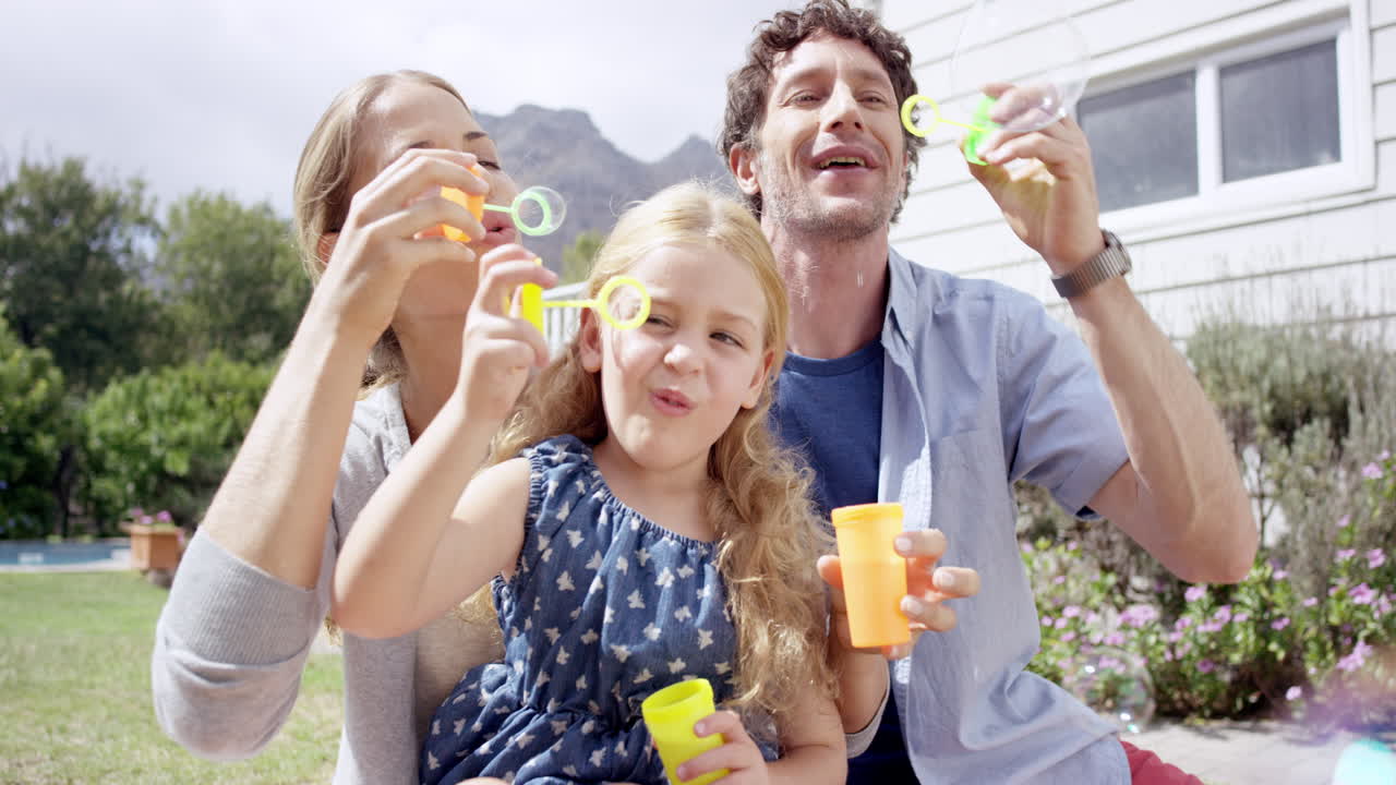 행복 한 가족 이 집 의 마당 에서 거품 을 불어넣고 있다