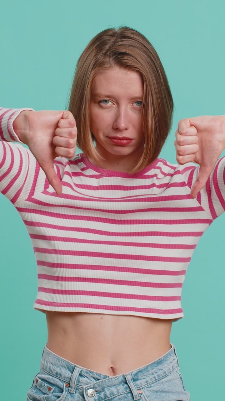 Upset attractive young woman lady showing thumbs down sign gesture disapproval dissatisfied dislike