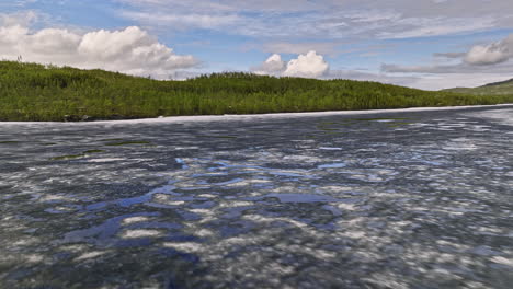 takvatnet norway v1 low level drone flyover melting icy lake wit beautiful sky reflection on the water surface surrounded by lush green forest and mountainscape - shot with mavic 3 cine - june 2022