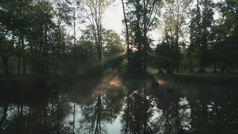 Hermoso-Amanecer-En-El-Lago,-Donde-Los-Rayos-Del-Sol-Brillan-A-Través-De-La-Niebla