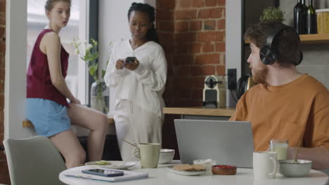 boy with headphones working on laptop computer during breakfast in a shared flat 1