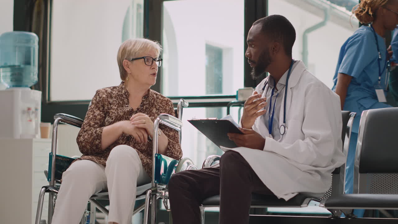 Senior woman with impairment talking to specialist in hospital reception