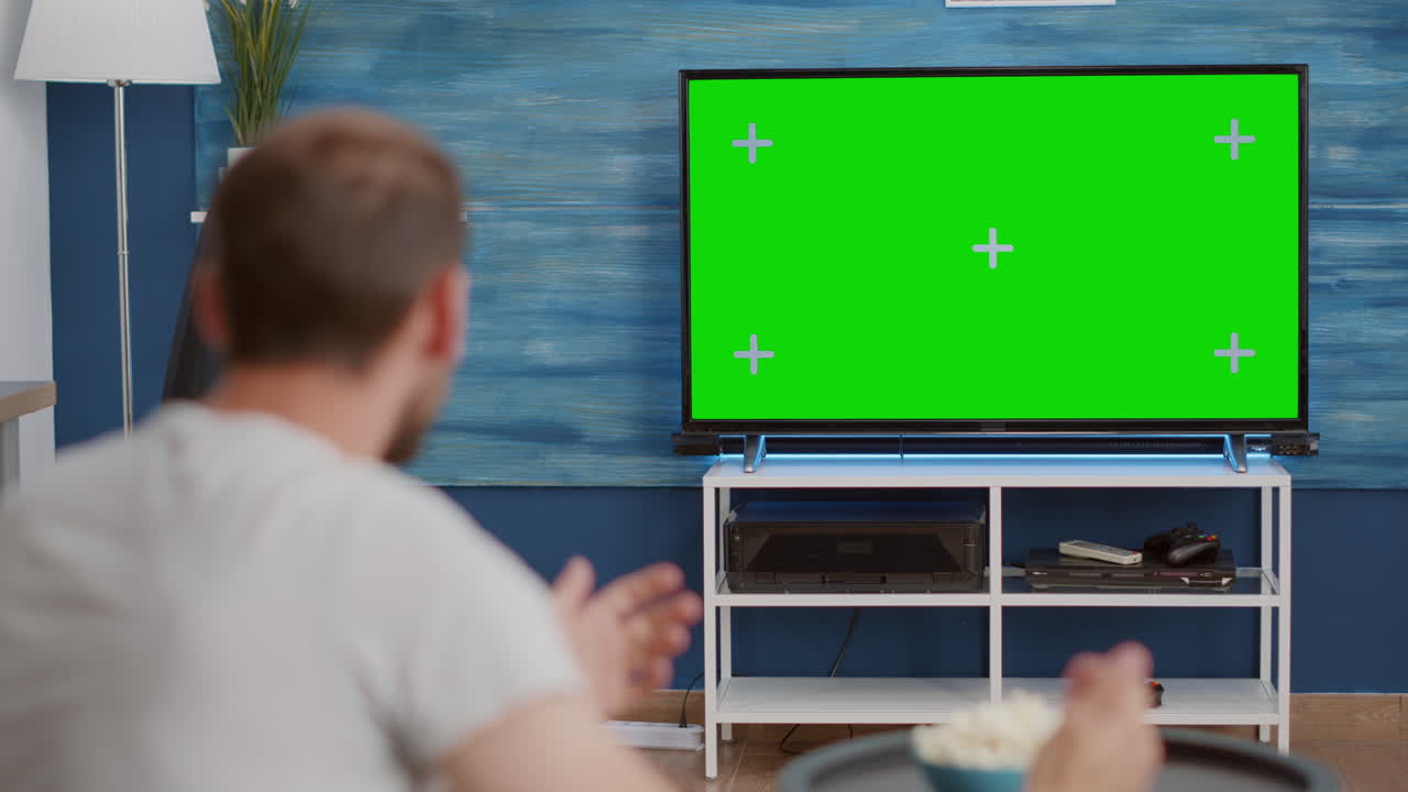 Over shoulder view of sports fan watching game on green screen tv mockup encouraging favourite team