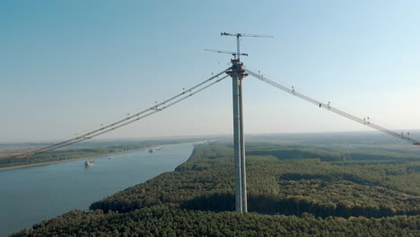 concrete column and cranes surrounded by green trees by the danube riverbank