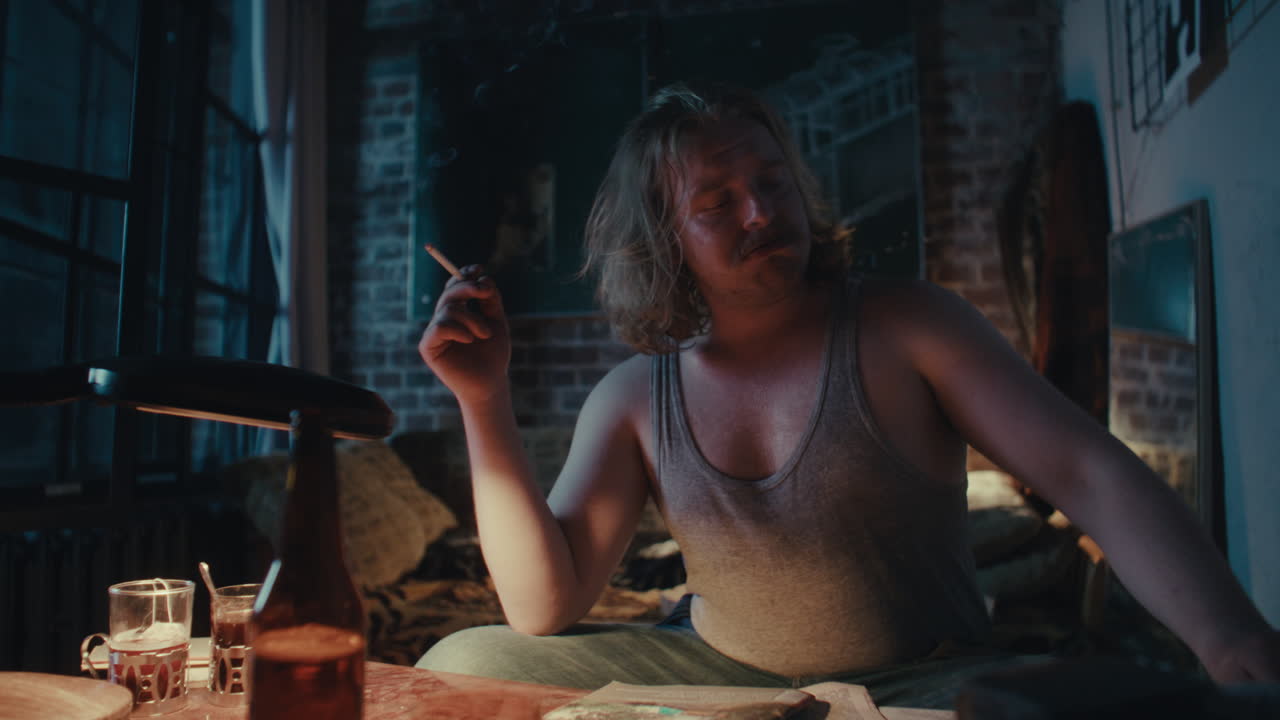 Um Homem Fumando em um Ambiente com Pouca Luz