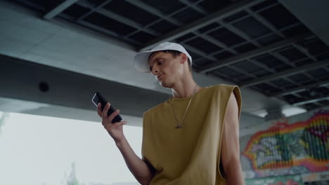 young skater checking social media on smartphone sitting at skate park.