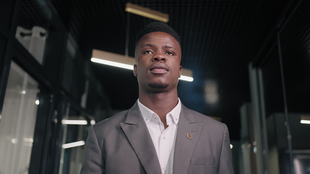 retrato de un hombre de negocios enfocado caminando en una reunión en el pasillo de la oficina. primer plano de un hombre afroamericano caminando en el corredor. un hombre de negocios afro serio yendo con una carpeta en el vestíbulo del centro de negocios.