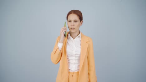 사업가 여성이 전화로 이야기하는 동안 방해받고 화를 내고 있습니다.