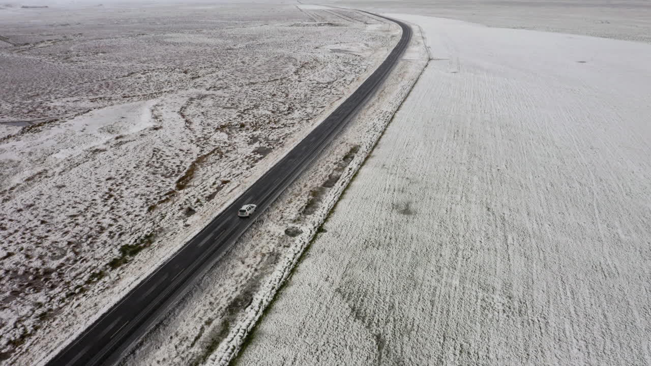 Aerial: Side follow of a car driving on snowy road