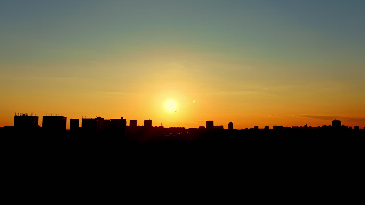 Puesta de sol sobre el horizonte de una ciudad con siluetas oscuras de edificios contra el cielo colorido al atardecer