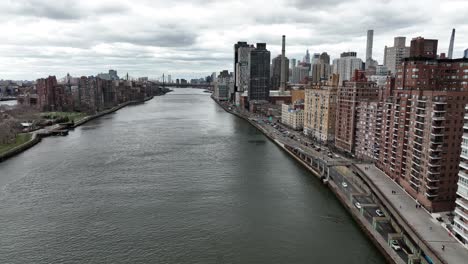 An-aerial-view-over-the-east-river-with-Roosevelt-Island-on-the-left-and-Manhattan's-Eastside-on-the-right,-taken-on-a-cloudy-day