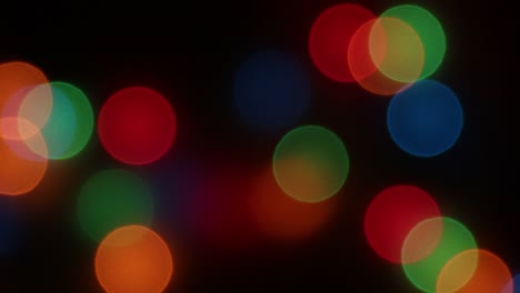 panning of defocused christmas lights in dark background