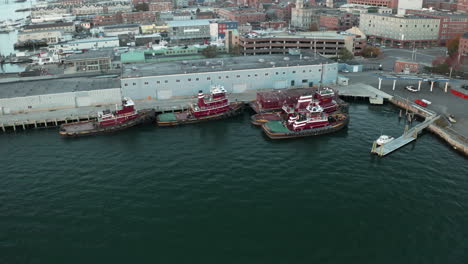 Aerial-Orbit-Drone-footage-of-tugboats-docked-at-wharf-in-Portland,-Maine,-USA