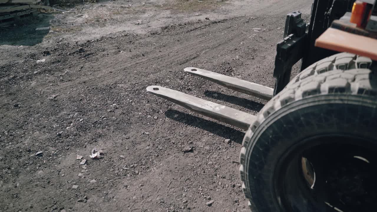 a forklift is approaching the pallet with bricks and lifting it to moving to another place in the street.