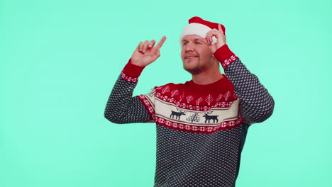 Man-in-Christmas-sweater-listening-music-via-earphones,-dancing-disco-fooling-around-having-fun