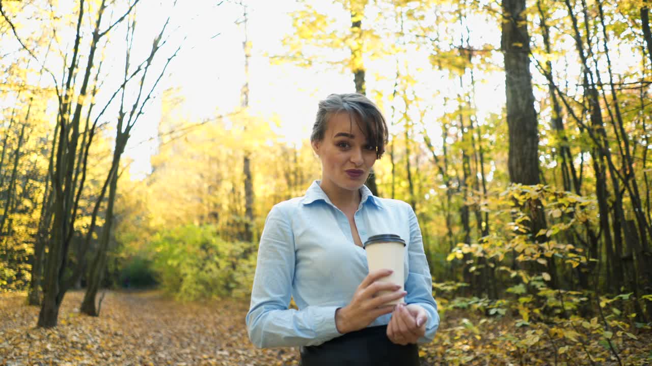 Woman spending time in park. Young woman spending time with cup of coffee in autumn park