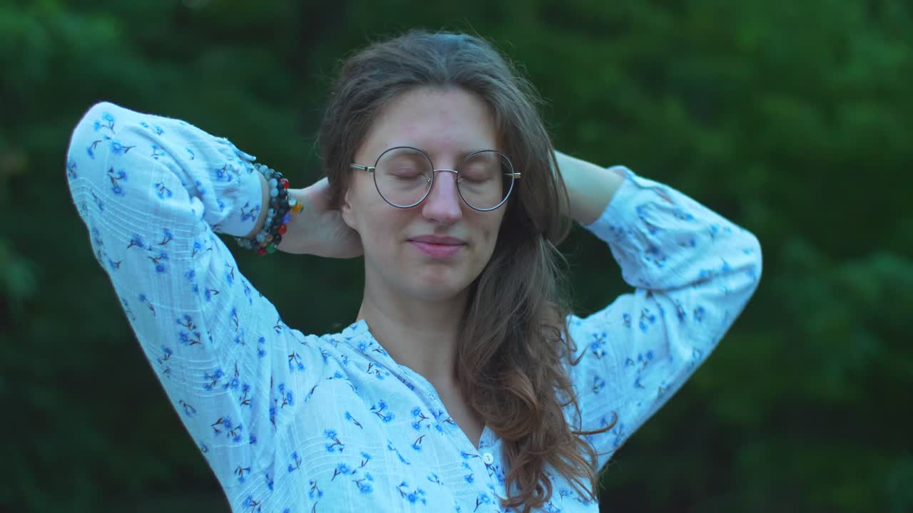 uma jovem mulher cuidando e acomodando seu cabelo ao ar livre