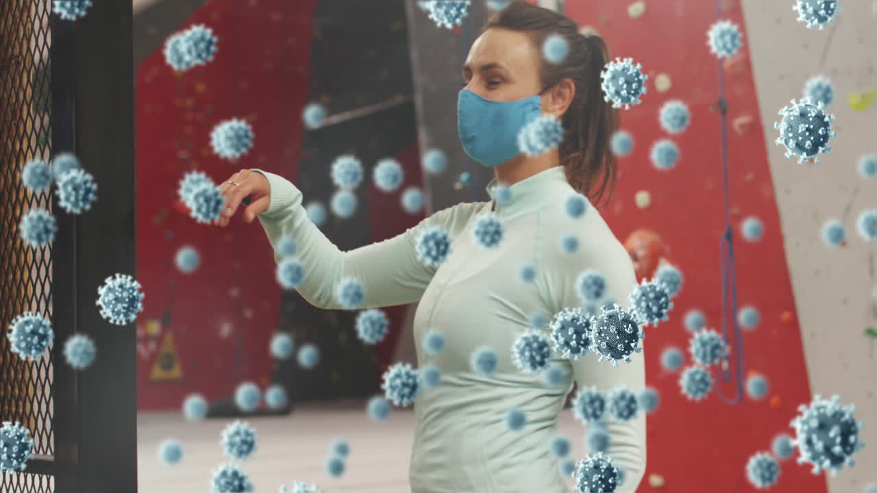 múltiples células de covid-19 flotando contra el retrato de una mujer caucásica con una máscara en el gimnasio