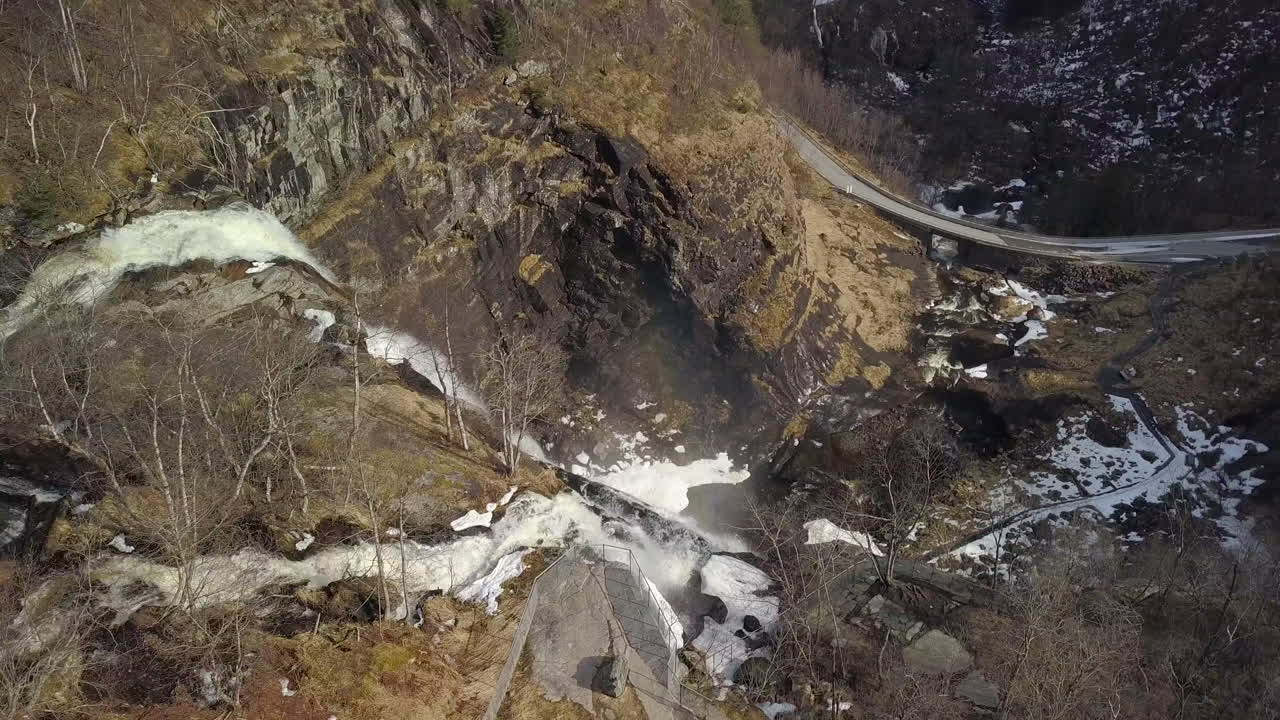 vista aérea inclinada hacia abajo sobrevolando una enorme cascada en noruega al comienzo de la primavera