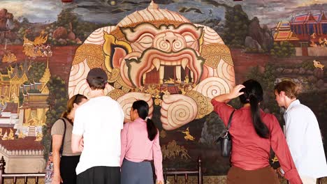 group observes intricate mural in bangkok temple