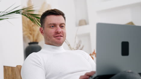 man finishes his work on laptop and closes his gadget. tired man leans back in his armchair relaxing after work.