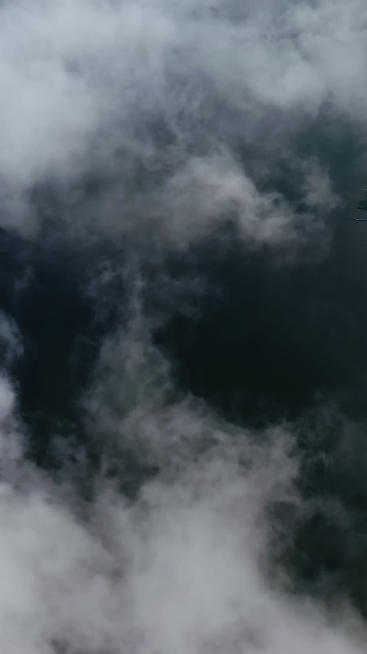 Amazing view from the sky. Flight among clouds on water background near the countryside. Aerial view. Vertical video