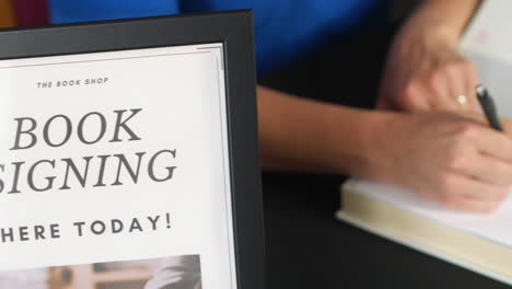 Panning-shot-of-an-unrecognizable-author-at-a-book-signing