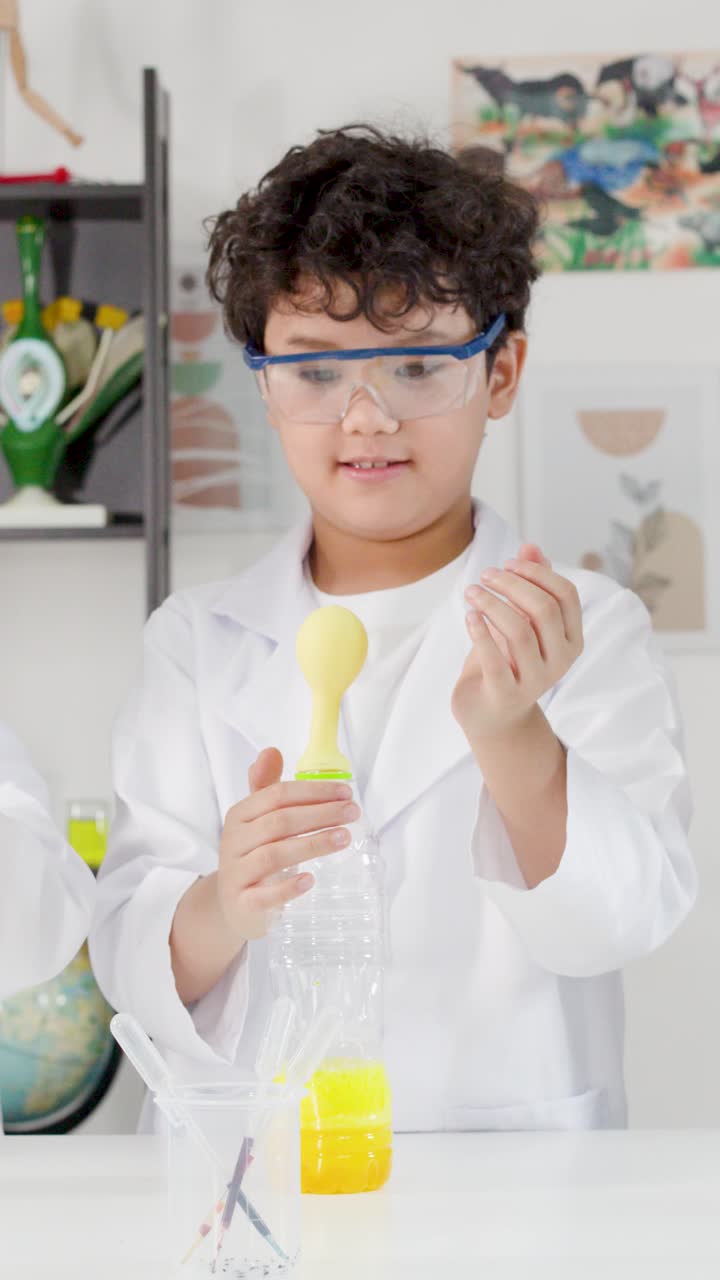 Seorang siswa muda berjas lab memasang balon pada percobaan botol plastik.