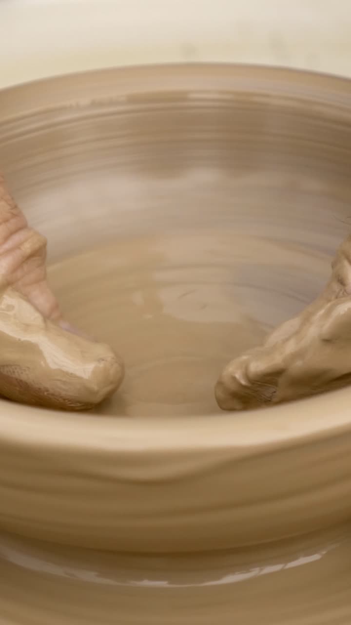Hand shaping a bowl on a pottery wheel