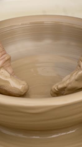 hand shaping a bowl on a pottery wheel