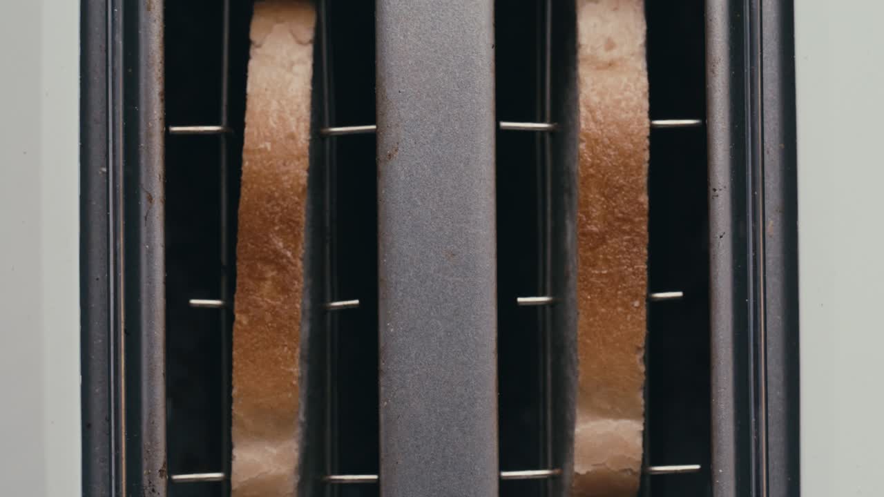 Close-Up View of Hand Inserting Bread Slices into Toaster