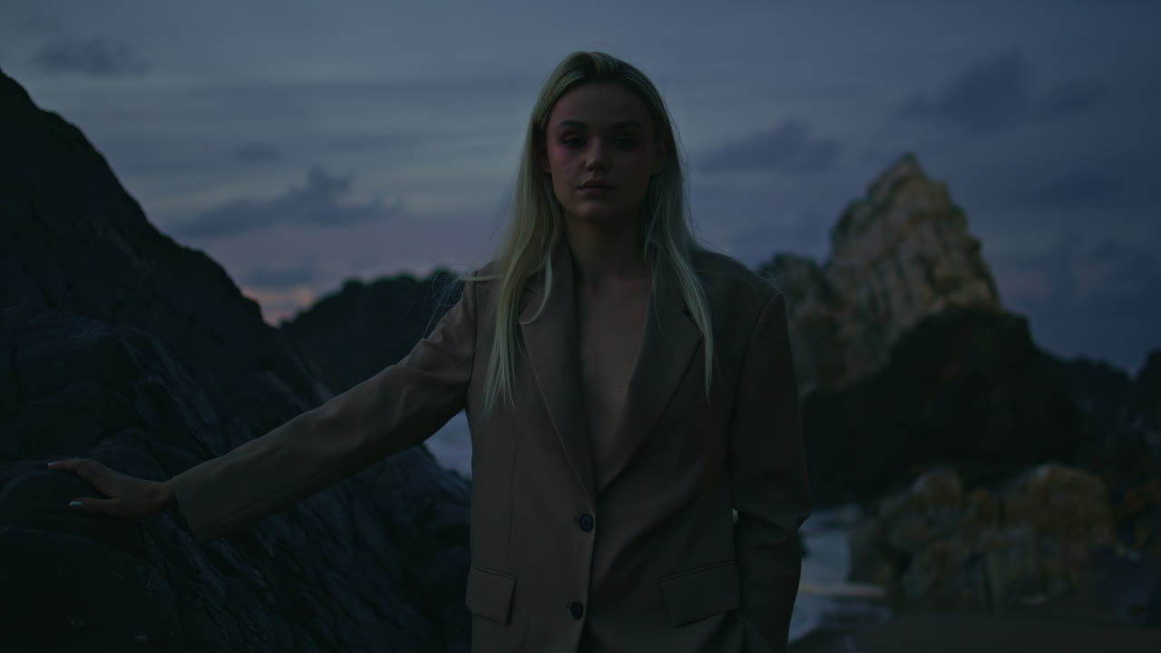 modelo rubio con luz parpadeante en la noche en la orilla del océano. chica sexy mirando la cámara