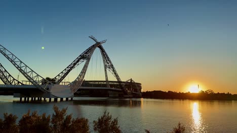 golden sunrise on the swan river with the matagarup bridge and perth optus stadium
