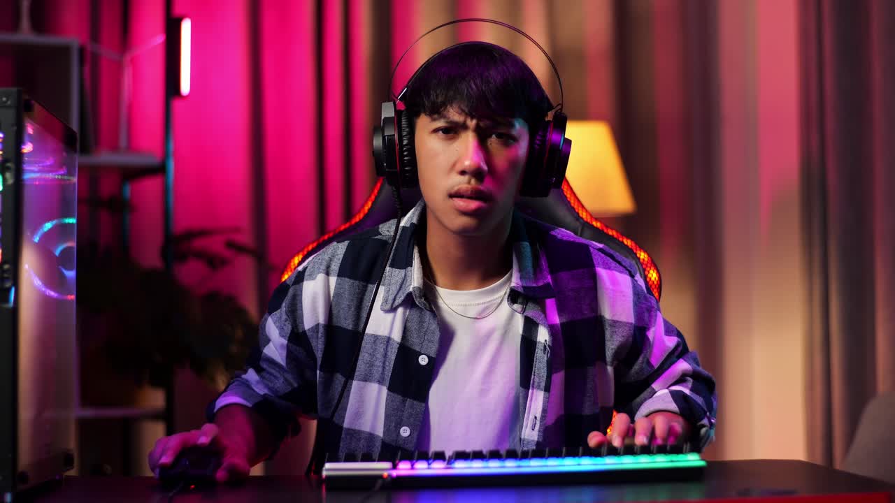 Vista frontal de gamer adolescente asiático perde enquanto joga videogame no computador
