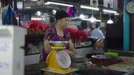 woman weighing and cutting fresh fish in a market