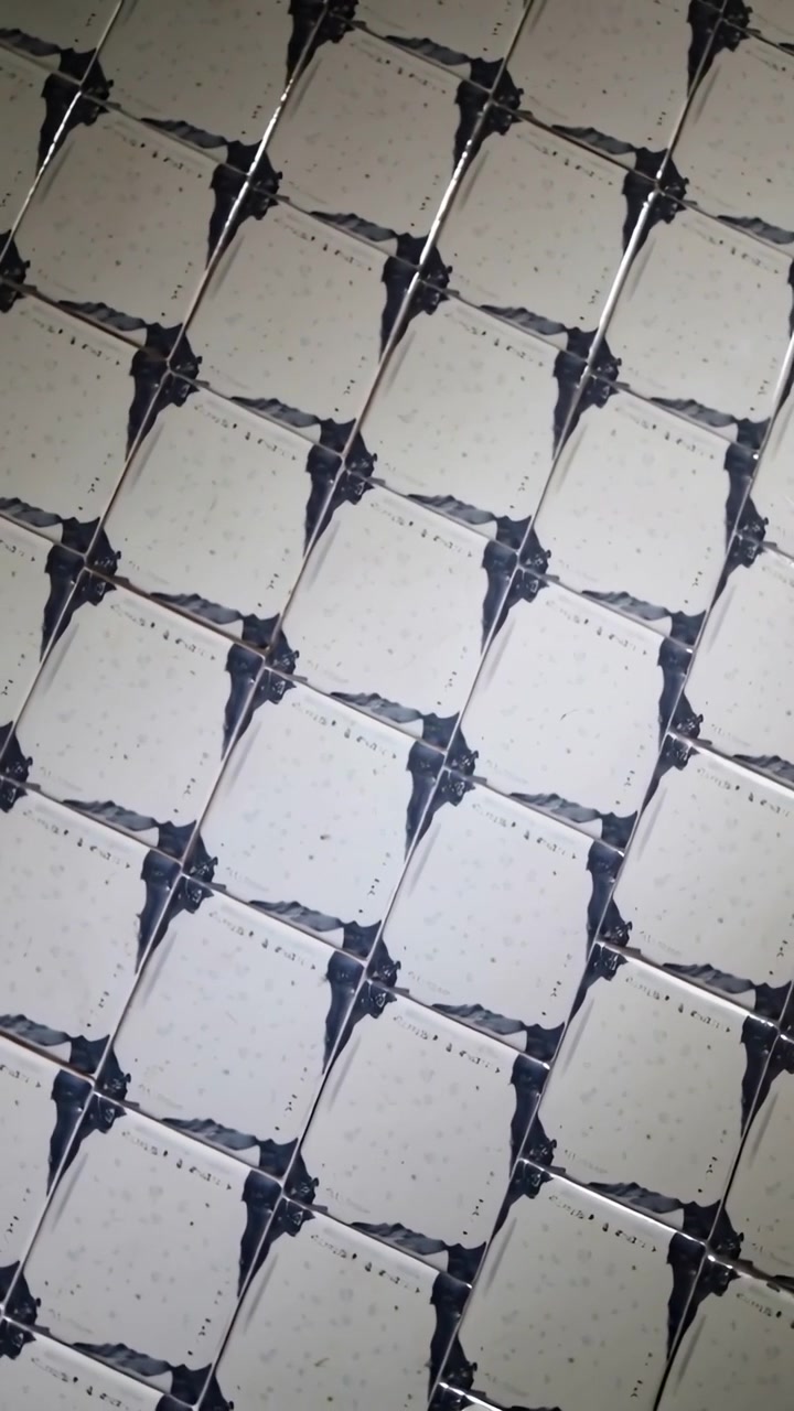 Vertical video: Rotating handheld revealing cream tiles with dark corners at wall, moving highlight
