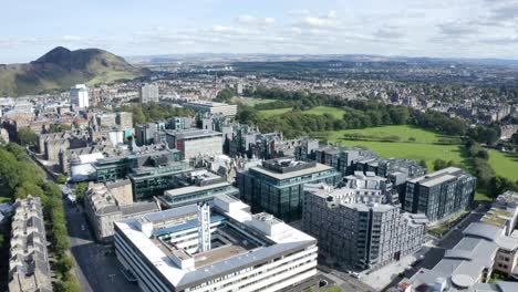 Aerial-shot-over-Edinburgh-University-buildings-and-the-Meadows,-towards-Arthur's-Seat,-on-a-sunny-day-|-Edinburgh,-Scotland-|-4K-at-30-fps