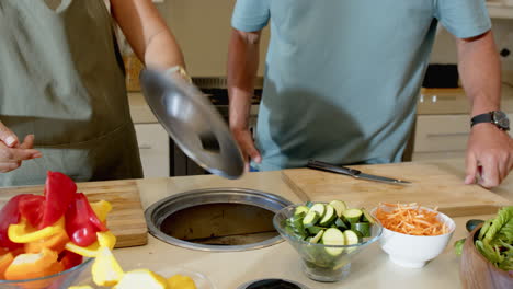 Senior diverse couple preparing meal together in kitchen, chopping fresh vegetables, at home