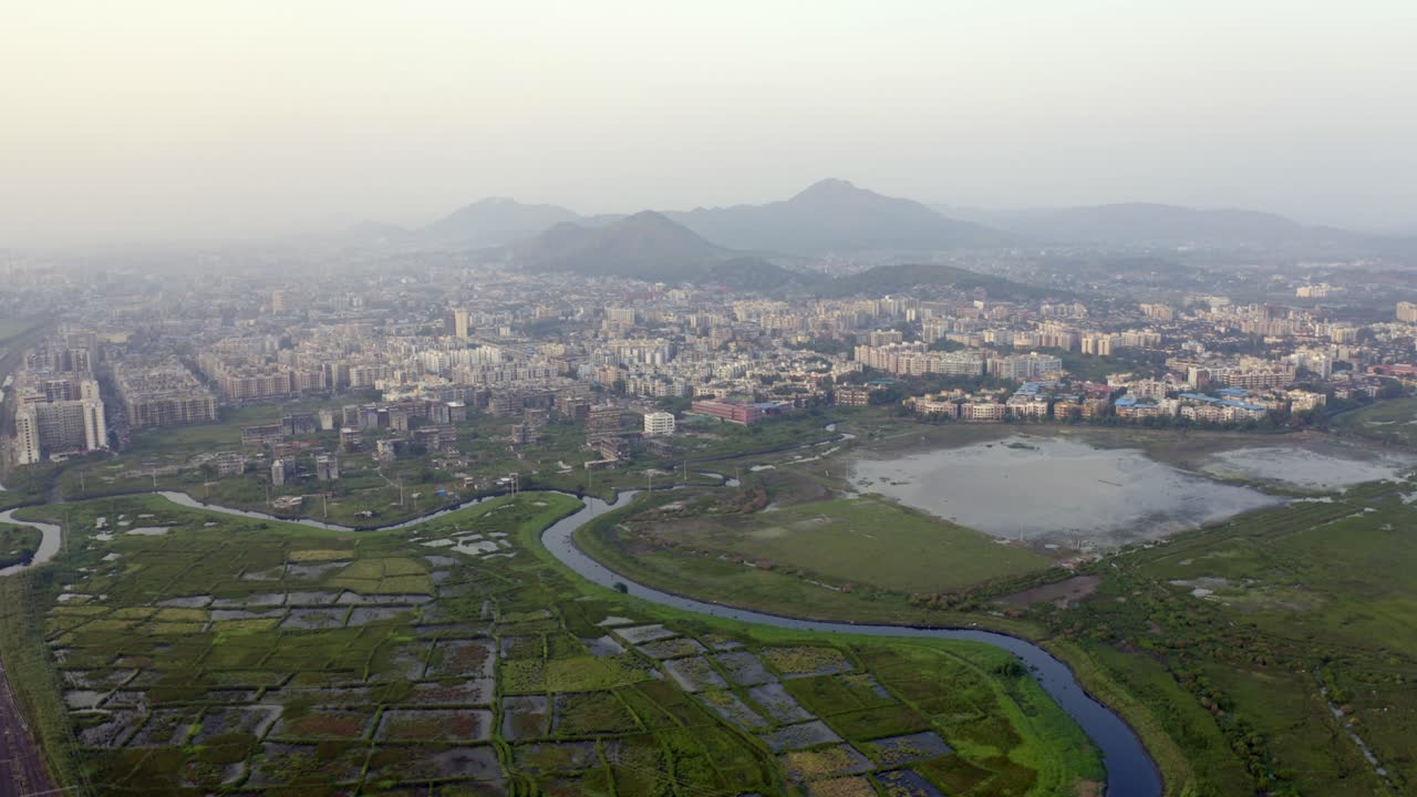 vista aérea de los edificios comunitarios, los campos y el arroyo en vasai east, vasai-virar maharashtra, india