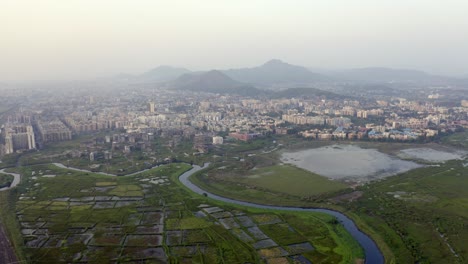 Vista-Aérea-De-Edificios-Comunitarios,-Campos-Y-Arroyos-En-Vasai-Este,-Vasai-virar-Maharashtra,-India