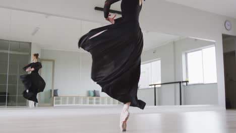 caucasian female ballet dancer practicing ballet during a dance class in a bright studio