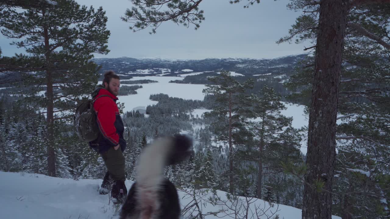 Escursionista con Alaskan Malamute tra montagne innevate e boscose