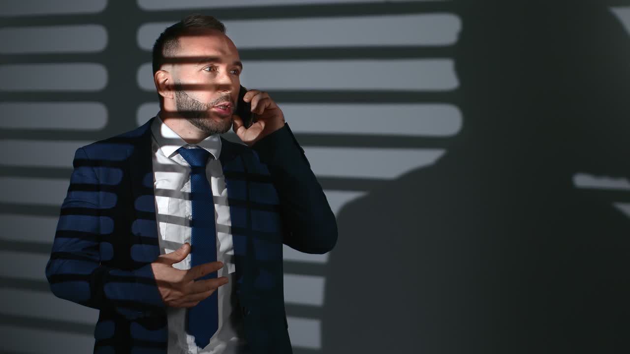 hombre de negocios confiado traje de corbata hablando teléfono inteligente discutiendo trabajo por la noche oficina celosía sombra