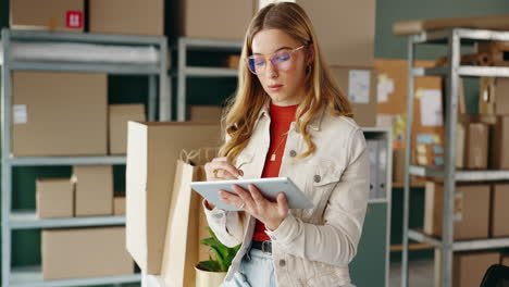 woman using tablet in warehouse surrounded by boxes